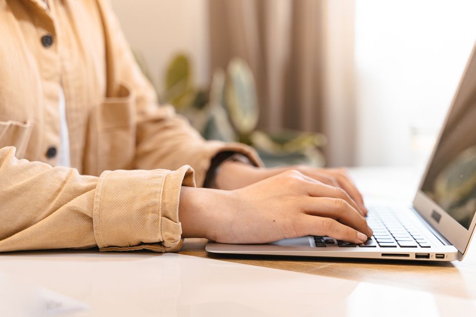 A professional and clean overhead shot of a person's hands typing on a laptop on an organized desk, representing the creation of expert, credible online content.